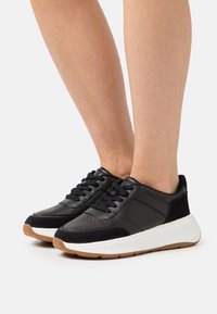 Sorte lærersneakers med suedeforsterkninger, hvit midtsåle og gummigummi yttersåle. Klassisk snøring design med perforerte detaljer.