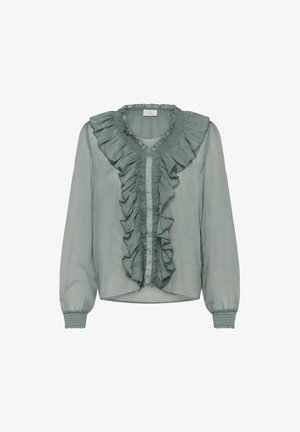 Šviesiai žalia, permatoma bluzonė su raukinėta priekiu, pilno ilgio rankovėmis ir elastiniais manchetais. Yra apskritas iškirpimas ir subtilus tekstūros raštas.