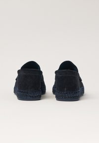 Marineblå ruskindssko med en tekstureret overflade, bagviewet viser en vævet espadrillesål i en mørkere blå farve, afslappet design.