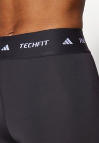 Zwarte sportieve shorts met een brede elastische tailleband voorzien van "TECHFIT" en logo in het wit. Glad materiaal, nauwsluitend design.