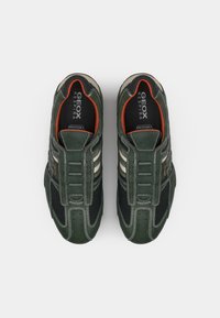 Ciemnozielone sneakersy z siateczkowymi detalami, gumowymi podeszwami, szarymi i beżowymi akcentami oraz teksturowanymi nałożeniami. Wewnątrz znajdują się oznaczenia "GEOX RESPIRA".