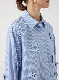 Blue striped shirt with large fabric flower appliqués in a light blue tone. Features a classic collar and button-down front.