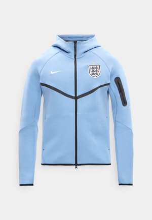 Ανοιχτό γαλάζιο φούτερ Nike με φερμουάρ, με το έμβλημα της ποδοσφαιρικής ομάδας της Αγγλίας στο στήθος, μαύρο φερμουάρ, τσέπη στο μανίκι και μαύρη επένδυση στα μανίκια και στο κάτω μέρος.