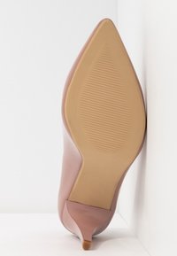 Escarpin à talon aiguille en cuir verni rose avec un bout pointu. Semelle texturée et légère avec un petit talon décoratif. Fini lisse avec des coutures détaillées.