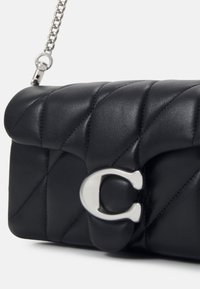 Sac à main en cuir noir matelassé avec bandoulière chaîne argentée et fermoir en "C" argenté sur le rabat avant.