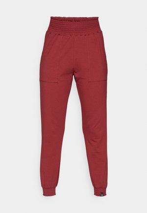 Pantalons joggers rouges taille haute avec taille élastique et bords élastiques, présentant des poches plaquées à l'avant et une coupe slim et fuselée.