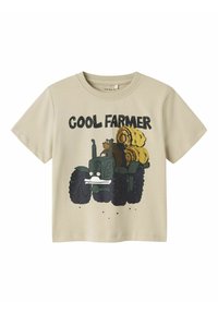 Camiseta de algodón beige con mangas cortas, que presenta un diseño impreso de un oso en un tractor verde con pacas de heno y el texto "COOL FARMER."