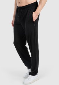 Schwarze, lässig geschnittene Hose aus weichem Material, mit einem elastischen Bund, seitlichen Taschen und geradem Bein.