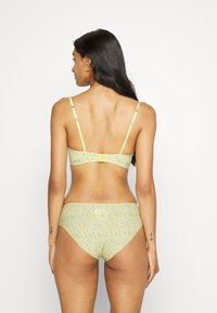 Conjunto de lingerie floral amarelo claro com fecho nas costas e alças ajustáveis. Tecido suave com uma textura subtil e detalhes de design.