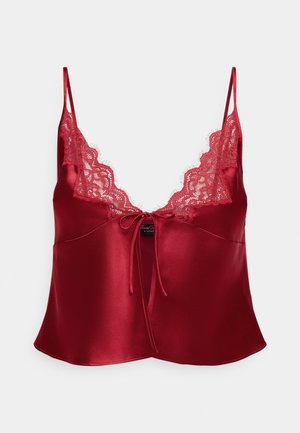 Red satin camisole featuring delicate lace trim along the neckline, adjustable spaghetti straps, and a cinched front tie detail.
