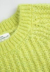 Zielono-limonkowy sweter z dzianiny z prążkowanym kołnierzem i fakturowanym wzorem. Metka widoczna na szwie kołnierza, podkreślająca markę.