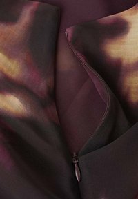 Prúdiaca tkanina s kombináciou tmavo fialovej a hnedej farby s jemným vzorom tie-dye. Obsahuje skrytý zips.
