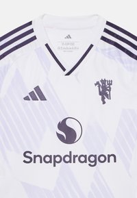 Baltas Adidas marškinėliai su purpuriniais akcentais, V formos kaklo iškirpte, trimis peties juostelėmis, su logotipu ir grafiniu raštu. Po logotipu esantis tekstas skaito "Snapdragon".