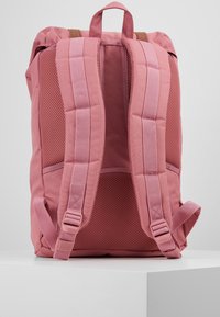 Sac à dos rose avec des bretelles rembourrées en mesh, une poignée supérieure et des sangles latérales réglables. Tissu durable avec des coutures renforcées et sans logos visibles.