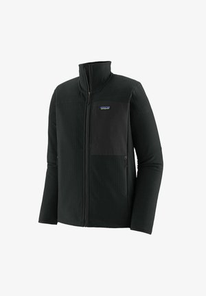 Mustmust veste, millel on lukuga eesmine osa, kõrge krae ja kontrastne must tasku, millel on kogu ulatuses peened tekstuurilised detailid.