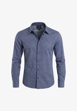 Camisa azul de manga larga con botones y un patrón geométrico blanco, con cuello abierto, mostrada sobre un fondo blanco liso.