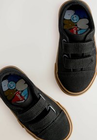 Zwarte canvas schoenen met twee klittenbandsluitingen, rubberen zolen en een multikleurig grafisch ontwerp van de binnenzool met cartoonfiguren.