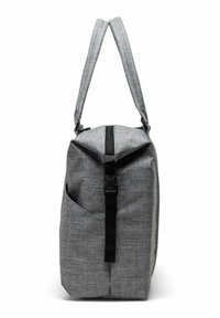 Sac en tissu gris avec une fermeture roulée, une sangle noire ajustable et une poche latérale. Il présente un matériau texturé et tissé.