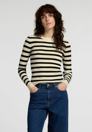 Creme- og sortstribet ribbet sweater med lange ærmer, rund halsudskæring og tætsiddende design, parret med mørkeblå højtaljede jeans.