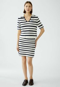 Gestreiftes Kleid in Weiß und Marineblau mit V-Ausschnitt, kurzen Ärmeln und gewelltem Saum. Mit fettem Text "QUI QUI" auf der Brust.