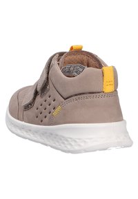 Šedé semišové tenisky s bílou podrážkou, suchým zipem, perforovanými detaily po stranách a žlutým poutkem na patě pro snadné obutí a styl.