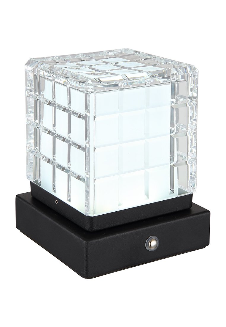 Przezroczysta szklana lampa w kształcie sześcianu z teksturowanym wzorem w kratkę na górze, umieszczona na matowej, czarnej prostokątnej podstawie. Posiada przycisk zasilania.