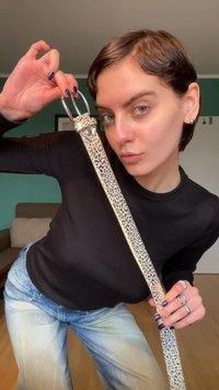 Leren riem met luipaardprint, voorzien van een glanzende zilveren gesp. Het ontwerp is langwerpig met een gladde textuur en een neutrale achtergrond.