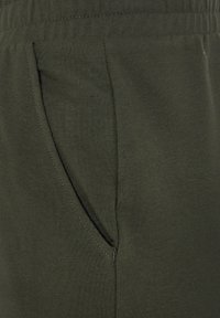 Olijfgroene joggingbroek van zacht katoen, met een zijzak en een elastische tailleband voor comfort. Gladde textuur met nette stiksels.
