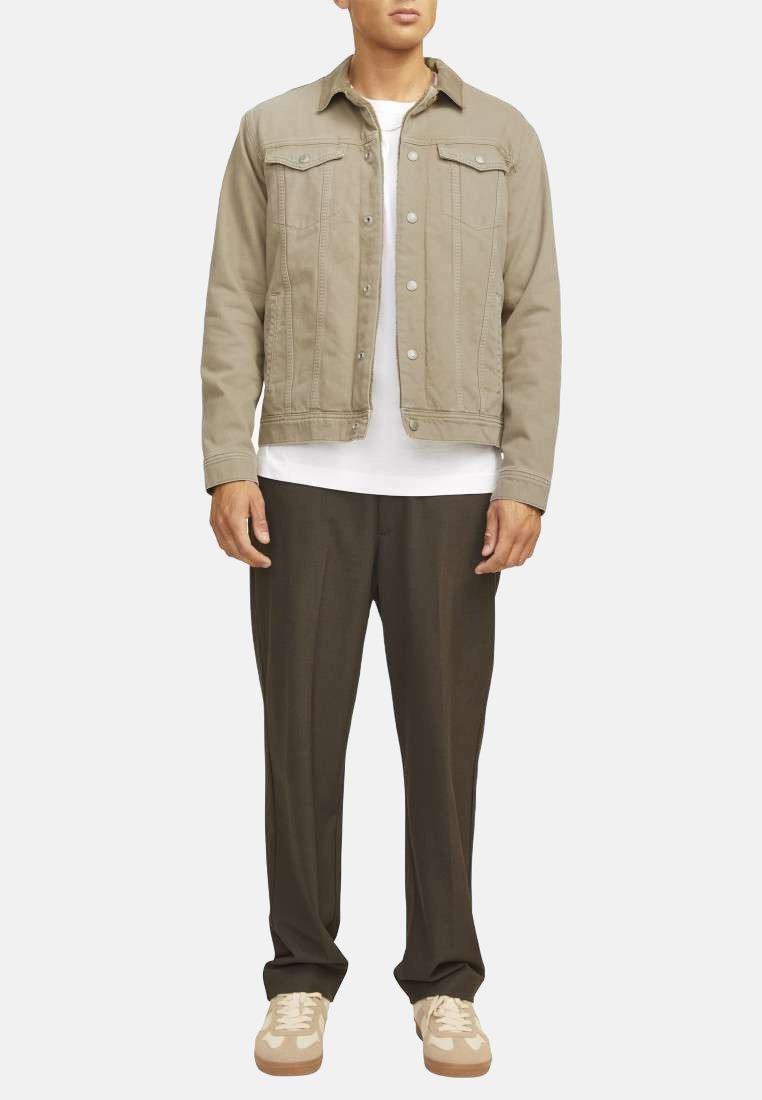 Veste en denim kaki avec col pointu, boutons avant, poches à rabat et t-shirt beige à col rond ; associé à un pantalon sombre et des baskets claires.