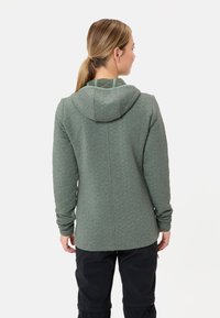 Getailleerde groene hoodie met een gestructureerd, gewatteerd patroon, met een capuchon en lange mouwen. De achterkant toont een centrale naad en zijzakken.
