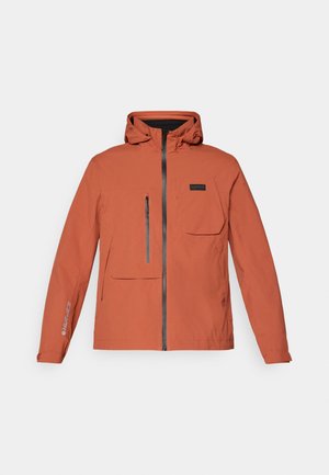 Chaqueta impermeable naranja con capucha, cierre frontal con cremallera, bolsillo en el pecho y puños ajustables. Presenta un logo en la manga. Textura suave.