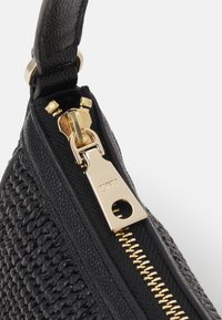 Bolso de mano negro tejido con un acabado texturizado, que cuenta con una cremallera dorada y un tirador para el cierre. Diseño de marca sutil en la cremallera.