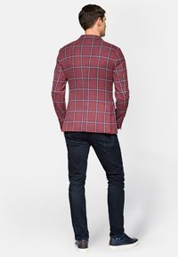 Bordowy żakiet w kraty wykonany z teksturowanej tkaniny. Posiada kontrastowe niebieskie i białe linie, dopasowany fason, noszony z ciemnymi wąskimi dżinsami i trampkami.
