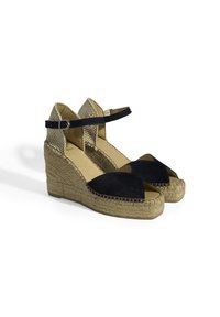 Espadrilles compensées en suède bleu marine avec une semelle en jute, présentant des découpes et une fine lanière à la cheville avec une boucle en métal. Tissu texturé sur les côtés.