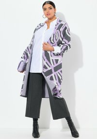 Lila und graue gemusterte Strickjacke mit entspannter Passform, getragen über einer weißen Bluse und grauen Hosen. Verfügt über lange Ärmel und offenen Vorderteil.