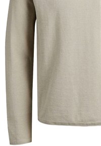 Camisa beige de manga larga hecha de tejido texturizado, con dobladillo redondeado y corte recto. Sin logotipos visibles ni patrones distintivos.