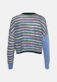 Wielokolorowy sweter z dzianiny, z falistymi wzorami w kolorze fioletowym, zielonym i białym, z niebieskim rękawem. Czarny prążkowany kołnierz i dół.