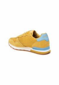 Baskets en suede jaune avec un accent bleu clair sur le talon, dotées d'une semelle rembourrée et d'un design à lacets à l'avant. Surfaces lisses et texturées.