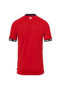 Camiseta deportiva roja de manga corta, con cuello y puños negros que presentan acentos en blanco con el logo "Kempa" en las mangas. Tejido suave y ligero.