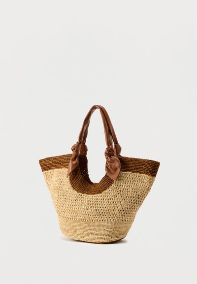 Πλεκτή τσάντα ώμου από άχυρο με καφέ δερμάτινη χειρολαβή και δίχρωμο σχέδιο που συνδυάζει υφή καφέ και φυσικού άχυρου.