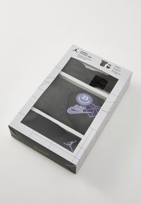 Jordan 3-delt sett emballasje har et gjennomsiktig vindu som viser en svart hettegenser, shortser og sportsstrømper med lilla detaljer og logoer.