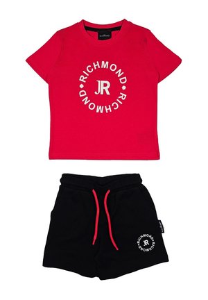 T-shirt in cotone rosso con testo grafico circolare bianco e logo; abbinato a pantaloni corti neri con elastico in vita e lacci rossi.