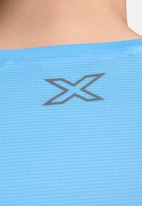 Heled sinine spordipaita, millel on ruuduline tekstuur; tumehall logo, mis asub seljal kaela lähedal.