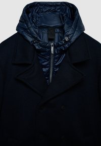 Marineblauer zweireihiger Mantel mit gerippter Textur, ausgestattet mit abnehmbarer wattierter Kapuze, silbernem Reißverschluss und Kordelzug-Details.
