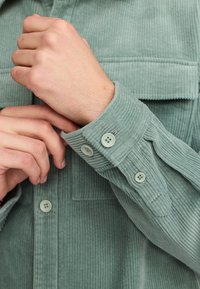 Lichtgroene corduroy shirt met ribbelstructuur, met een borstzak en een knoopmanchet met bijpassende knoppen.