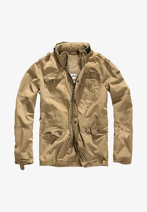 Khakis spalvos striukė, pagaminta iš patvarios medžiagos, su aukštu apykakle, užtrauktuko uždarymu ir keliais kišenėmis su sagų sklendėmis. Struktūruotas paviršius pagerina dizainą.