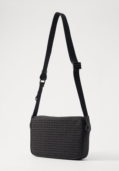 Black synthetic shoulder bag with repeating "Emporio Armani" logo pattern, adjustable strap, zip closure, and smooth texture.