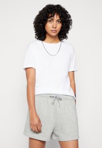 T-shirt en coton blanc à manches courtes, associé à un short en coton gris avec une taille élastique et un cordon de serrage.