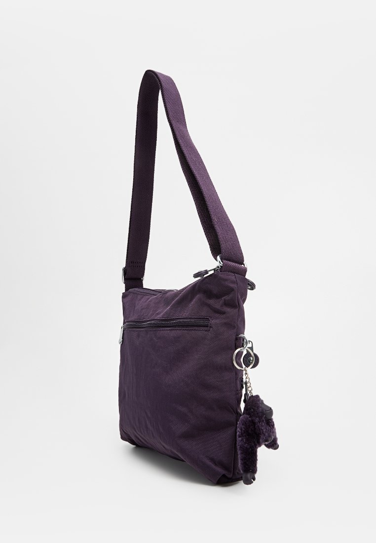 Borsa a spalla in tessuto viola con tracolla regolabile, tasca frontale con zip e un accessorio a forma di chiave in peluche. Tessuto morbido e forma quadrata.