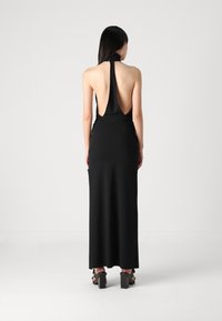 Melnas halter stila kleitas ar atvērtu aizmuguri, garu siluetu un gludu audumu. Satur plecu daļā frizūru detaļas un minimālisma dizainu.